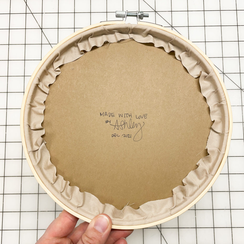 Finished back of hoop with kraft paper covering the middle, with a hand written note on the paper. 