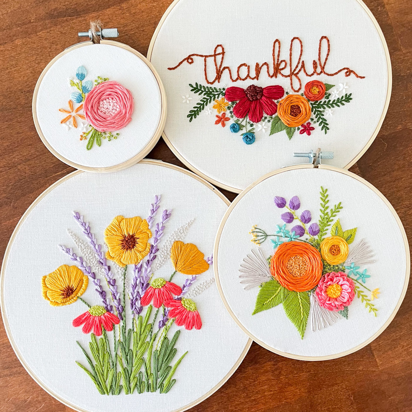 Picture of 4 embroidery hoops of different sizes. All feature flowers.