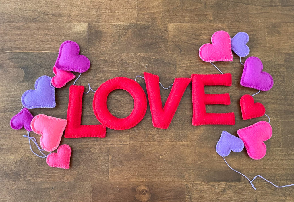 Image shows a DIY Valentines garland made of hearts and the word LOVE.