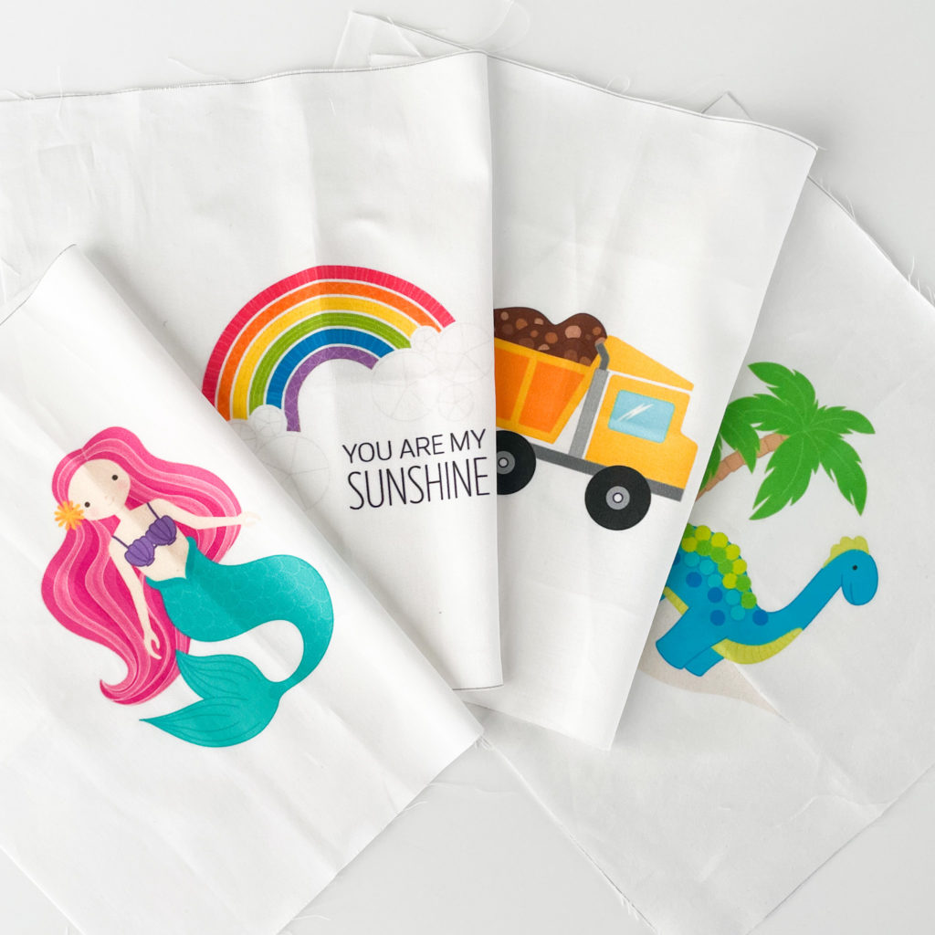 Unstitched, printed fabric for the kid embroidery kits. Show four different images, a mermaid, a rainbow, a dump truck, and a dinosaur.