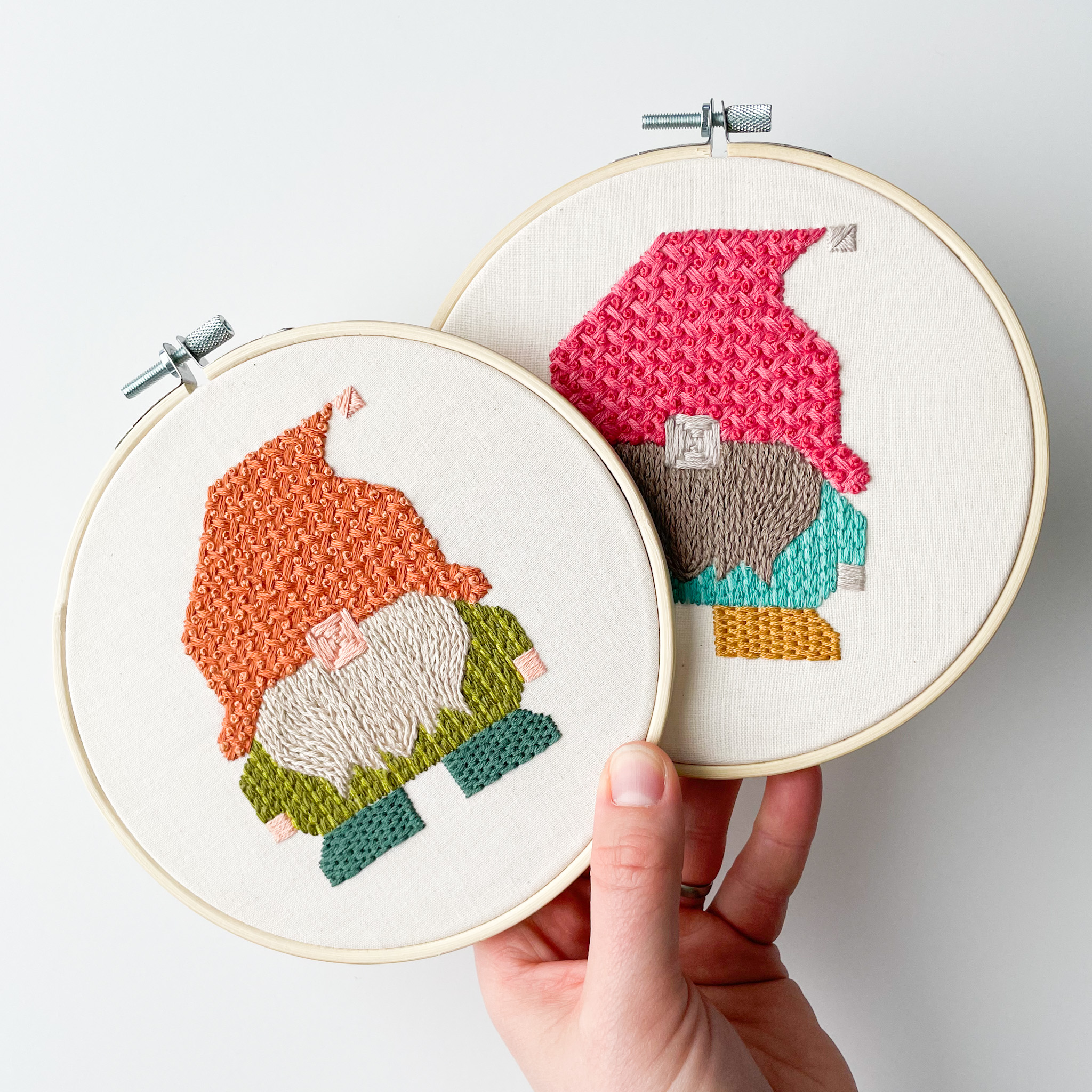 Two embroidery hoops with gnomes stitched on both. The embroidery's feature basket weave, stem stitch, backstitch, chain stitch, and brick stitch.
